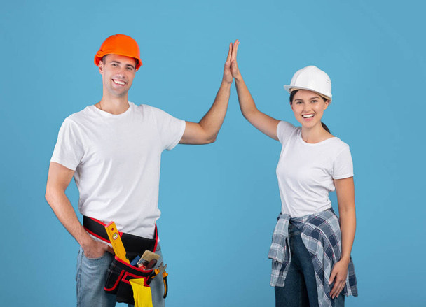 Trabalhadores alegres casal em chapéus duros dando alta cinco para o outro - Foto, Imagem