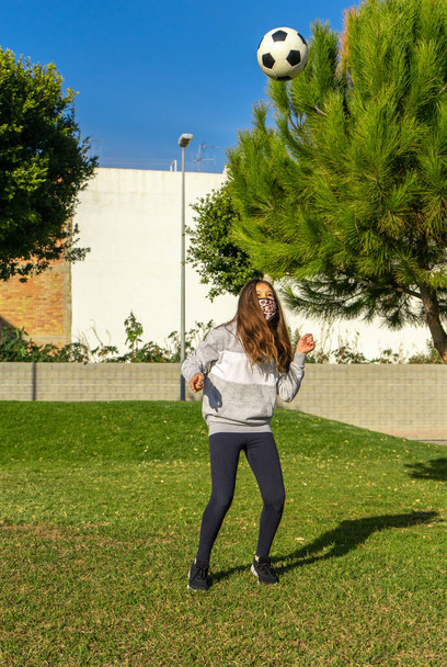 Menina bonita jogando futebol em um parque agradável com grama natural em um dia ensolarado de inverno. Exercício e conceito de vida saudável - Foto, Imagem
