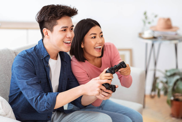 Happy Asian Couple Playing Videogame Having Fun On Weekend Indoor - 写真・画像