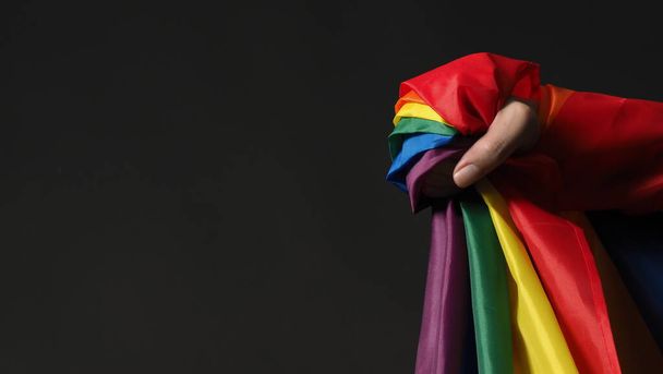 LGBTQの旗やレズビアンゲイ双方向性転換性的クィアや同性愛者のプライドの虹の旗が黒を背景に描かれている。自由、平和、平等と愛の手のシンボルを表します。LGBTQの概念 - 写真・画像