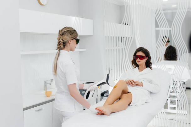 A beautiful young girl will undergo laser hair removal with modern equipment in a Spa salon. Beauty salon. Body care - Фото, зображення