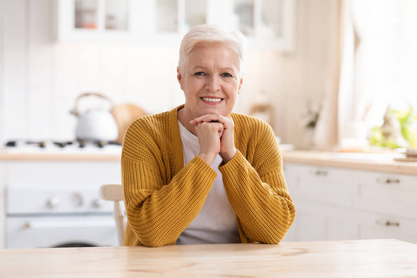 Portret van een vrolijke oude vrouw in de keuken - Foto, afbeelding