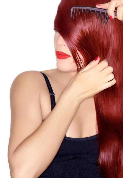 Hajfestés és hajápolás koncepció egy fiatal vörös hajú nő fésülködik a hosszú, fényes, egészséges haj az arcára, hogy esik kecsesen az egyik vállát elszigetelt fehér stúdió háttér - Fotó, kép