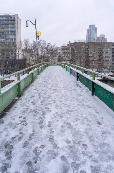 Parijs, Frankrijk - 01 16 2021: Een brug boven het kanaal van het bekken van de villette onder de sneeuw - Foto, afbeelding