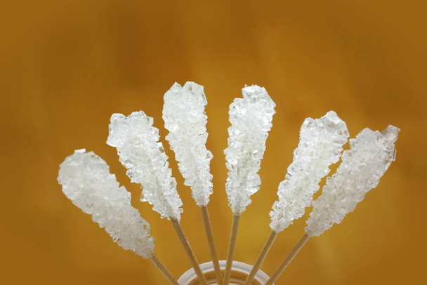 Witte suikerstokjes. Zes kristallen suikersticks geïsoleerd op bruine achtergrond - Foto, afbeelding