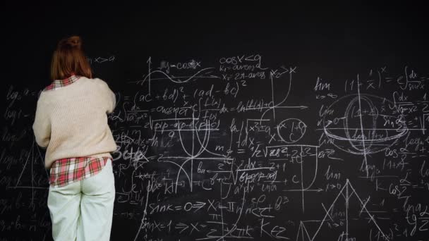 Mujer resuelve problemas científicos escribiendo fórmulas en pizarra centradas en estudios - Metraje, vídeo