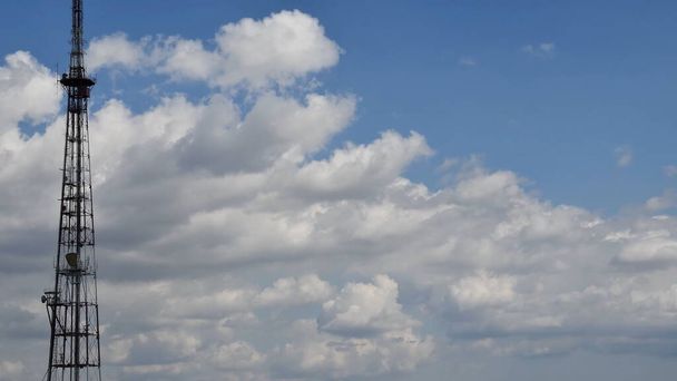 Alto céu azul e nuvens brancas flutuantes com silhueta de torre de comunicação - Foto, Imagem