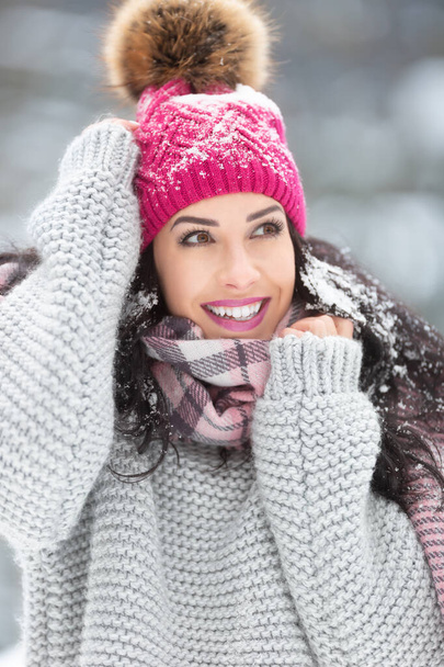 Trendy winter fashion outfit on a beautiful woman wearing sweater, scarf and pom pom hat. - Foto, afbeelding