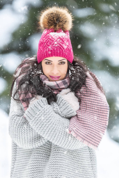 Winter fashion outdoors captured on a female model wearing ping pom pom hat, grey sweater and pink knitted scarf.  - Φωτογραφία, εικόνα