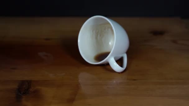 Camera beweegt naar de kantelbare kop koffie op natte houten tafel met zwarte achtergrond. Schot tegen object bewegen. - Video