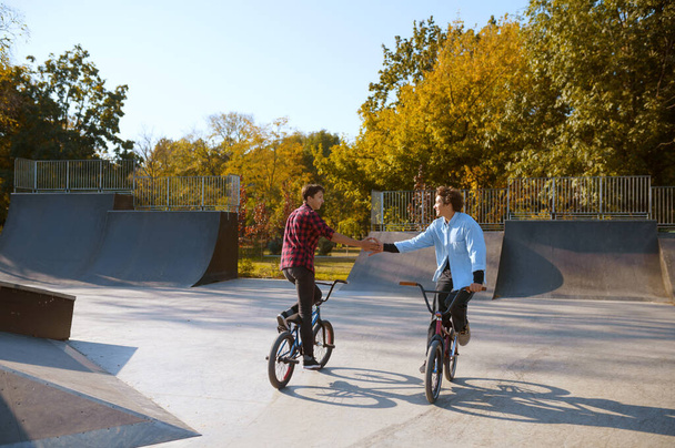 Dois motociclistas de bmx, a treinar em rampa no parque de skate. esporte de bicicleta extrema, exercício de ciclo perigoso, passeios de rua, ciclismo no parque de verão - Foto, Imagem