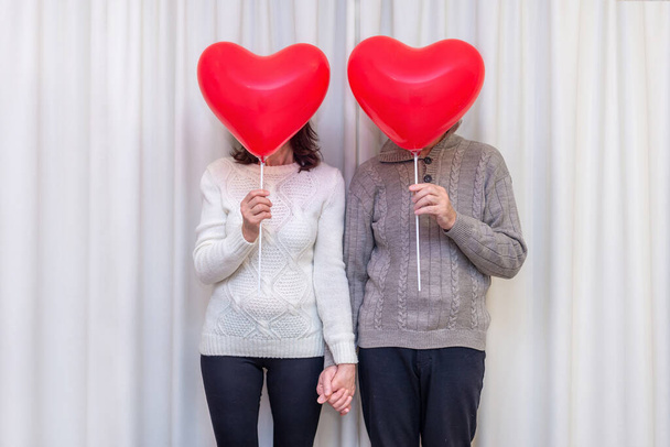 Happy couple seniors celebrate Valentines Day. Faceless couple with no face behind heart balloon. Romantic relationships, love and dating in retirement. Lifestyle of elderly people. Mature pensioners. - Photo, image
