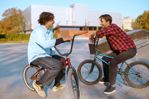 Bikers Bmx em bicicletas, formação em rampa no parque de skate. Extremo esporte de bicicleta, exercício de ciclo perigoso, passeios de rua, adolescentes de bicicleta no parque de verão - Foto, Imagem