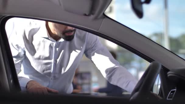 Acheteur satisfait regardant à l'intérieur de la voiture chez le concessionnaire - Séquence, vidéo