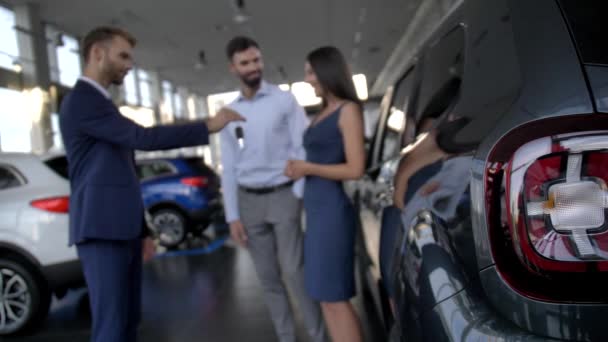 Rozmazaný radostný pár dostat klíček od auta v prodejně - Záběry, video