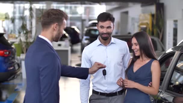 Χαρούμενο ζευγάρι που παίρνει το κλειδί για να αγοράσει αυτοκίνητο στο showroom - Πλάνα, βίντεο