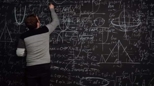 Il professore scrive equazione sulla lavagna piena di formule matematiche e punta il dito sorridente - Filmati, video