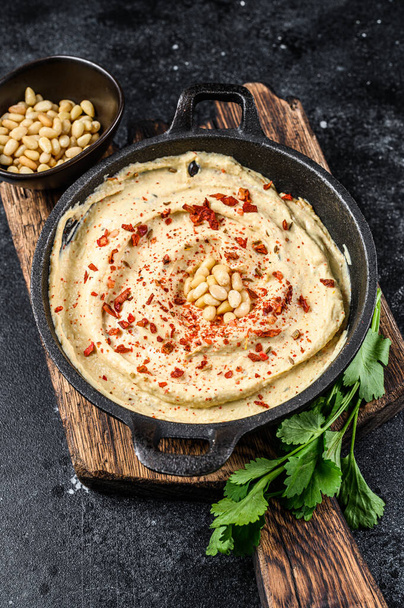 Hummus paste with chickpea and parsley in a bowl. Black background. Top view. - Foto, afbeelding