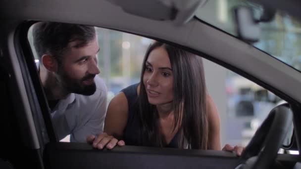 Szczęśliwa para patrząc wewnątrz samochodu w salonie - Materiał filmowy, wideo