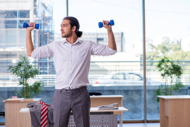 Young male employee doing sport exercises in the office - Photo, Image