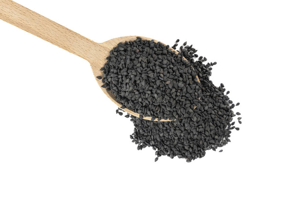 Czarne nasiona sezamu w drewnianej łyżeczce izolowane na białym tle. Przyprawy i składniki żywności. - Zdjęcie, obraz