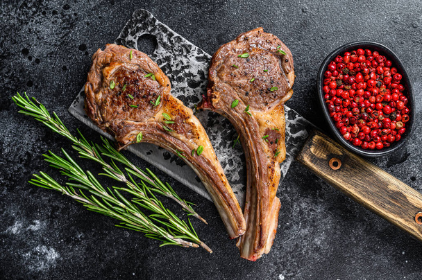 Barbecue grilled lamb chops on a butcher meat cleaver. Black background. Top view. - Fotó, kép