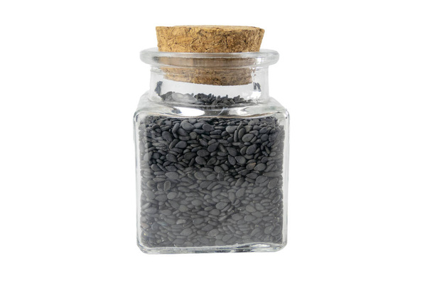 Semillas de sésamo negro en un frasco de vidrio aislado sobre fondo blanco. Especias e ingredientes alimentarios. - Foto, imagen