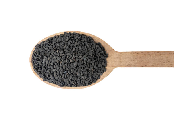 Czarne nasiona sezamu w drewnianej łyżeczce izolowane na białym tle. Przyprawy i składniki żywności. - Zdjęcie, obraz