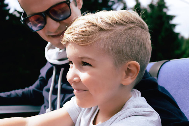 zbliżenie szczęśliwy dzieciak jeździć korzystając w ropeway jeździć dowcip jego ojciec w góry. - Zdjęcie, obraz