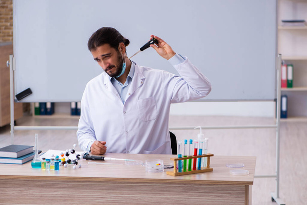 Nuori kemisti opettaja istuu luokkahuoneessa - Valokuva, kuva