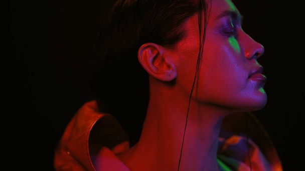 Sensual millennials girl in street style fashion night portrait of girl and neon lights. Portrait shot of a beautiful girl wearing down jacket in neon color lights. Night club, Party - Фото, изображение