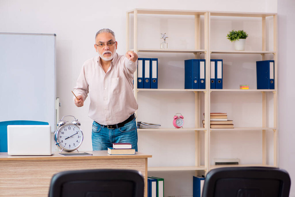 Old male teacher in the classroom in time management concept - Photo, Image