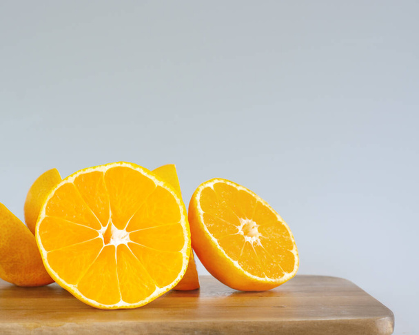 Piece of orange on cutting board on blurred gray background - Foto, afbeelding