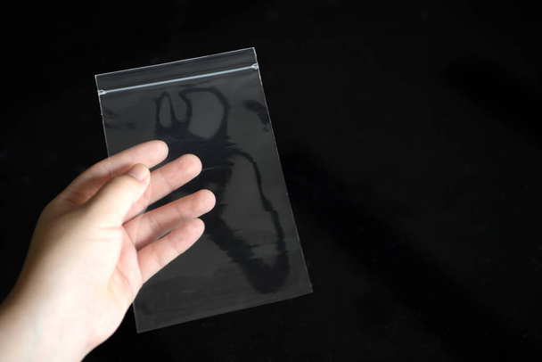 La bolsa de plástico con cremallera se recoge para mostrar transparencia sobre un fondo negro. - Foto, Imagen