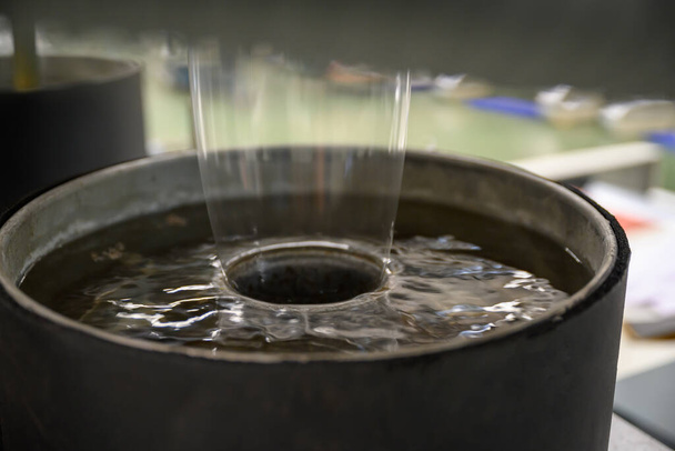 Plastový stroj na výrobu fólií Polypropylen Closeup ukazuje čirý plastový materiál tekoucí z hlavy zápustky do vaničky se studenou vodou na ochlazení plastu a jeho krásu. - Fotografie, Obrázek