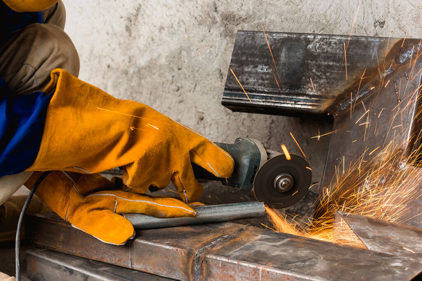 Closeup of a angle grinder being used to cut a notch inside a steel pipe. At a construction site. - Photo, Image