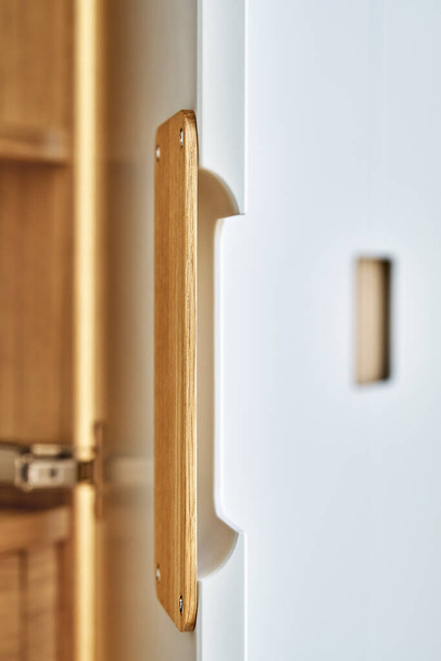 Detail of the wardrobe close-up. Modern wooden wardrobe with flat finger pull wardrobe doors. Oak veneered plywood cabinets with light gray painted cabinet doors. Modern furniture - Fotoğraf, Görsel