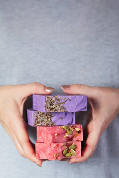 Female hands hold a stack of homemade handmade soap. The aroma of cherries and lavender. Small business, organic products, natural ingredients. - Photo, Image