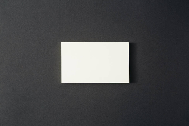 Белый прямоугольный лист бумаги лежит на черном фоне - Фото, изображение
