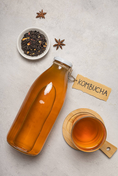 Kombucha bottle with "Kombucha" written on it and a glass of drink - 写真・画像