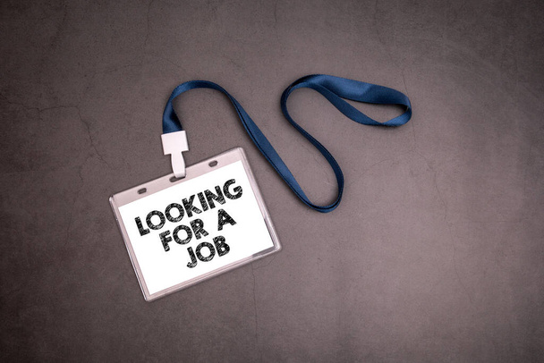 Suche nach einem Job. Namensschild mit blauem Band auf dunklem Hintergrund - Foto, Bild