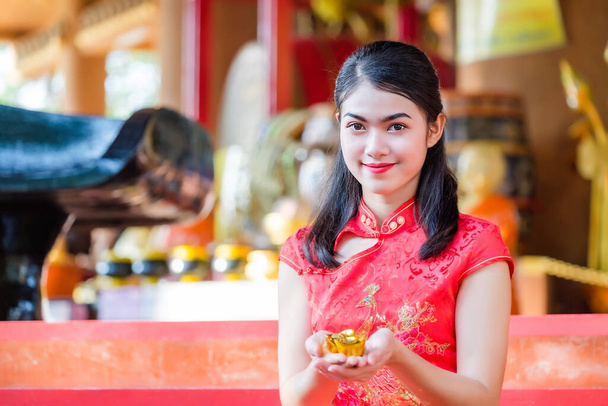 Ασιάτισσα με κόκκινο φόρεμα, Κινέζικη εθνότητα ευλογημένη με χρυσό στο χέρι. - Φωτογραφία, εικόνα