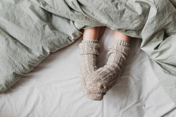 From under the blanket you can see children's feet with warm wool socks. - Foto, Imagem
