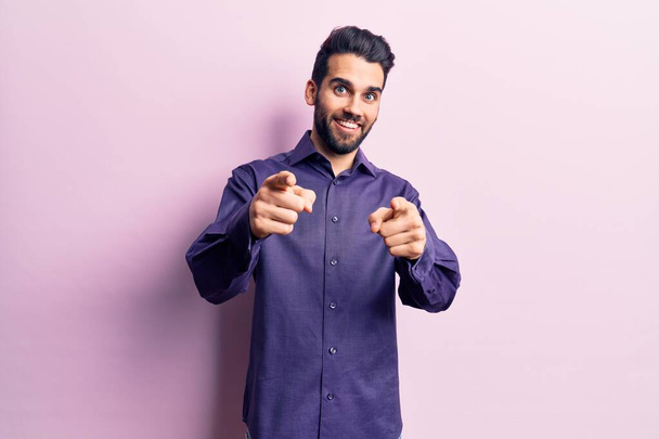 Young handsome man with beard wearing casual shirt pointing fingers to camera with happy and funny face. good energy and vibes.  - Photo, Image