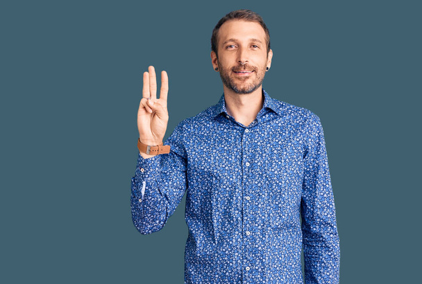 Young handsome man wearing casual clothes showing and pointing up with fingers number three while smiling confident and happy.  - Photo, Image