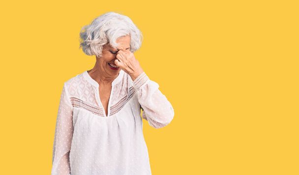 Старша сіро-волохата жінка в повсякденному одязі втомилася натирати ніс і очі, відчуваючи втому і головний біль. концепція стресу та розчарування
.  - Фото, зображення