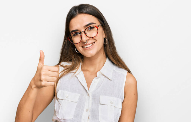 Junge hispanische Frau in lässiger Kleidung, die glücklich und positiv lächelt, Daumen hoch und Zeichen der Anerkennung  - Foto, Bild