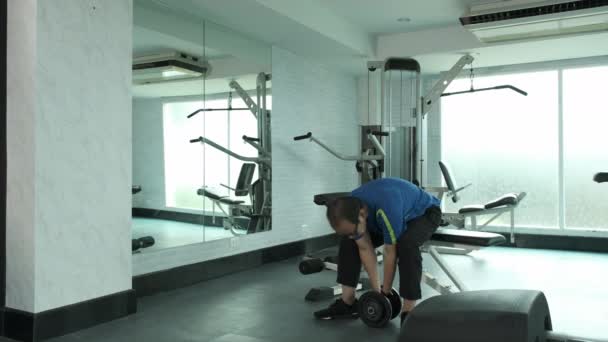 Junger asiatischer Mann in Sportkleidung übt French Press durch Hantelheben, um beim GYM Muskeln und Kraft aufzubauen. Sport, Bodybuilding, Fitness und People-Konzept  - Filmmaterial, Video