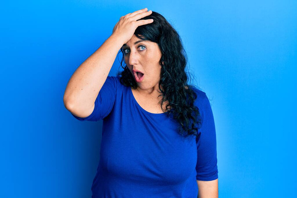Плюс розмір брюнетка жінка в повсякденній блакитній сорочці здивована рукою на голову за помилку, пам'ятайте про помилку. забута, погана концепція пам'яті
.  - Фото, зображення
