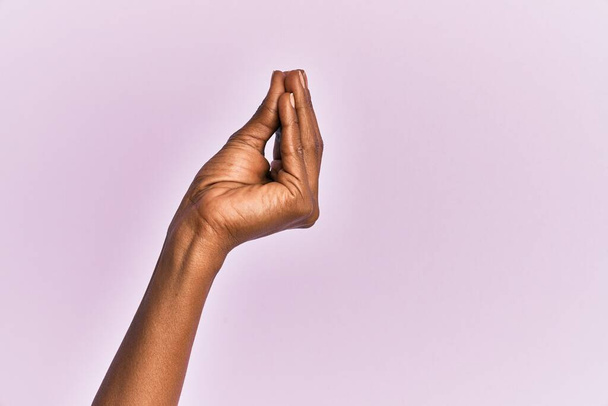 Χέρι και χέρι της μαύρης μεσήλικας γυναίκα πάνω από ροζ απομονωμένο φόντο κάνει ιταλική χειρονομία με τα δάχτυλα μαζί, κίνηση χειρονομία επικοινωνίας  - Φωτογραφία, εικόνα